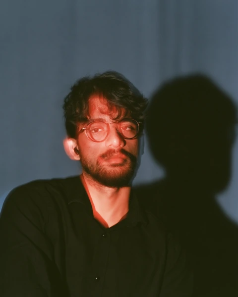 A black-and-white portrait of Advaith Gunna wearing glasses and a black shirt.